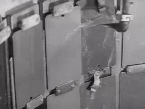 Water spraying onto metal test panels inside an industrial testing apparatus.