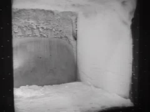 A technician removing a rack of tested metal panels from a snowy environment.