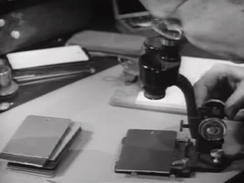 Microscopic inspection of test panels on a laboratory desk with specialized equipment.