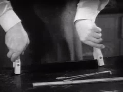 A person holding and inspecting a treated black material strip in a laboratory.