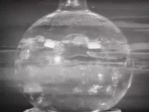 A glass flask with bubbling liquid superimposed over a cloudy sunset sky.