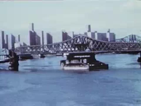 city skyline and bridge viewed through a wire fence
