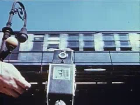 Close-up of a vintage camera mounted outdoors with a train passing by.