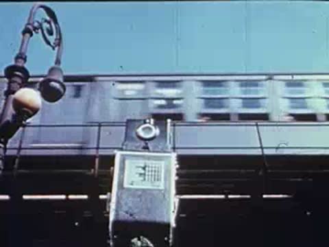 A train speeds past behind a camera mounted on a tripod outdoors.