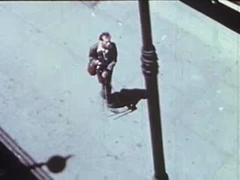 High-angle shot of a man standing on a sidewalk with a tripod.