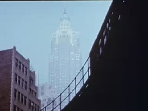 View from a train curving along elevated tracks toward a distant skyscraper.