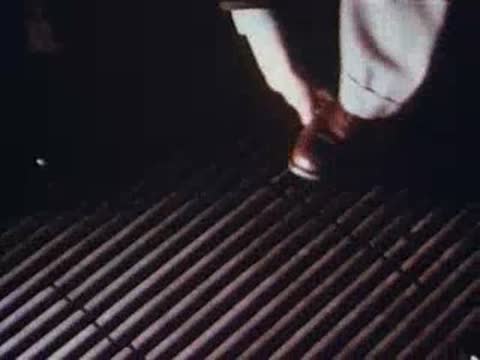 Coin dropped onto wooden grating outdoors, men's shoes visible, archival footage.
