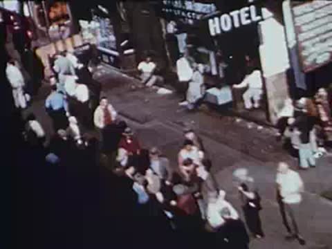 Crowd of pedestrians walking on busy city sidewalk near hotel, archival footage.