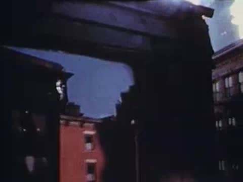 View between urban buildings showing sky and street below, archival footage.