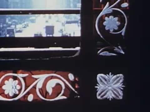 View from train window showing ornate metal grillwork and street scene, archival footage.
