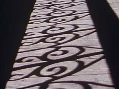 Geometric shadows cast on walkway by ornamental railing, archival footage.