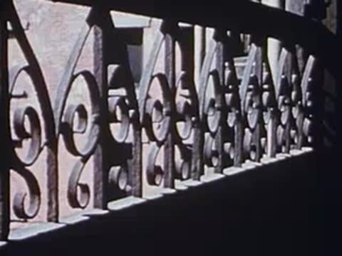 Ornate metal railing exterior staircase in bright sunlight, archival footage.
