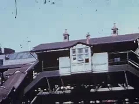 Exterior view of elevated train station building with small cupola, archival footage.