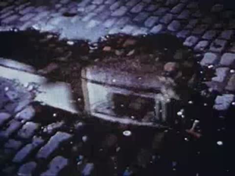 Street corner in Bowery with cobblestones and puddle reflection, archival footage.