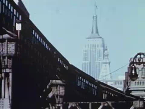 Elevated railway track with Empire State Building in background, archival footage.