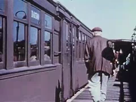 man walking along elevated train platform toward train cars