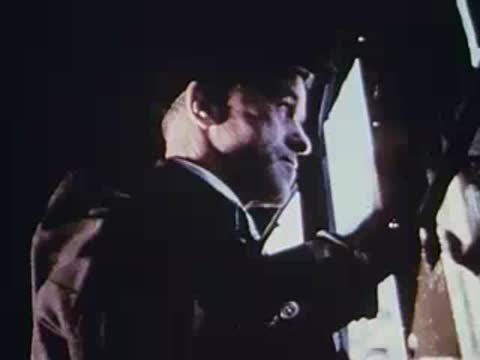man standing inside moving train holding onto strap