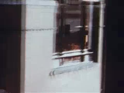 man looking out train window at city street