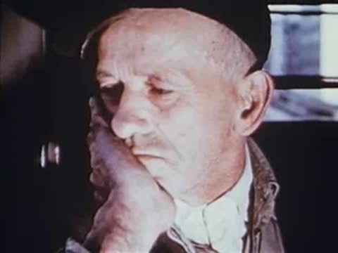elderly man sitting in train resting head on hand
