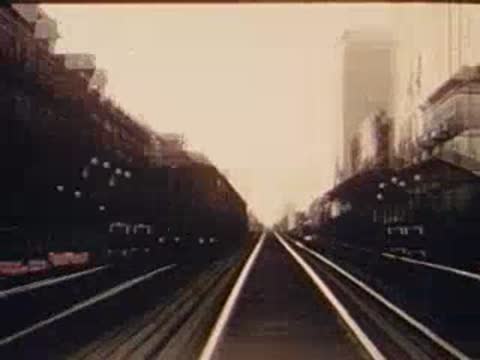 Forward tracking shot along elevated train tracks toward station.