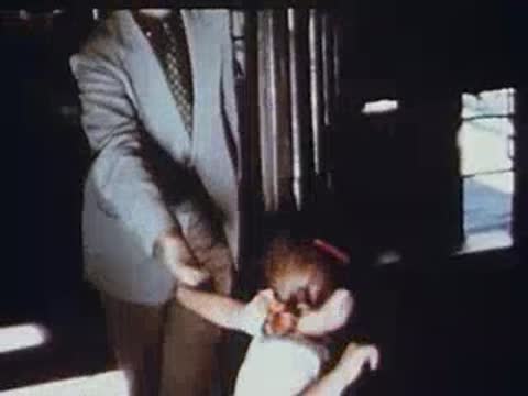 Little girl smiling while boarding a train with a man.