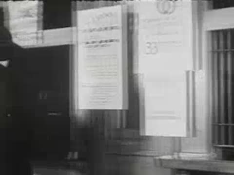 Woman at post office window mailing a package to clerk inside.