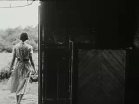 Woman walking away and exiting the barn through the open doorway.