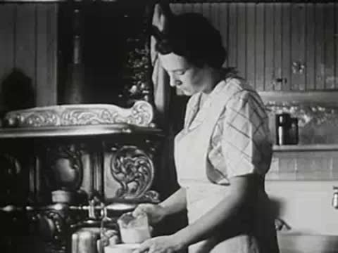 Woman preparing milk in a vintage kitchen by the stove.