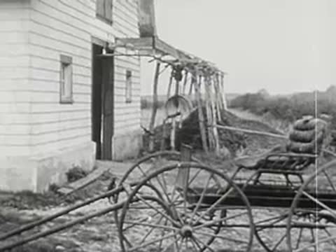 exterior view of a farmhouse with a horse-drawn cart and old-fashioned wagon wheels