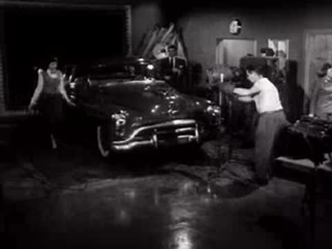 Wide view of the studio stage with a car, lights, and crew.