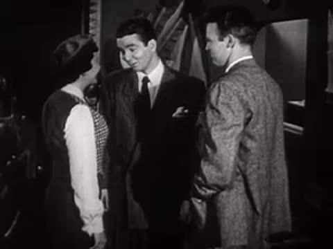 Woman and two men talking together inside an office or studio set.