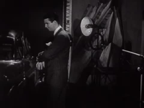 Man in a suit standing and looking down in an office or lab.