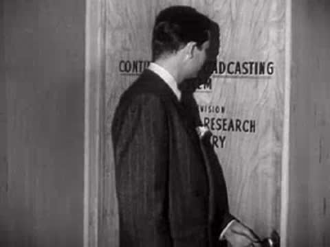 Man walking past a door marked Continental Broadcasting System Experimental Research Laboratory.