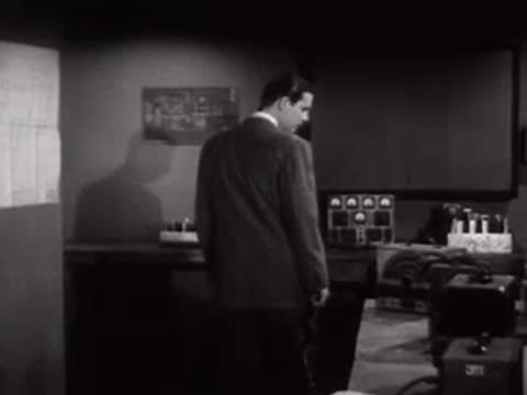 Man walking across a laboratory control room with electronic equipment.