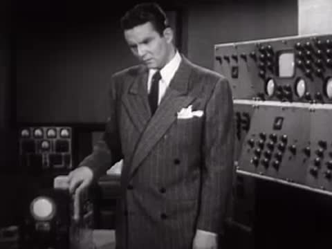 Man operating a large lever switch on an electronic control panel.