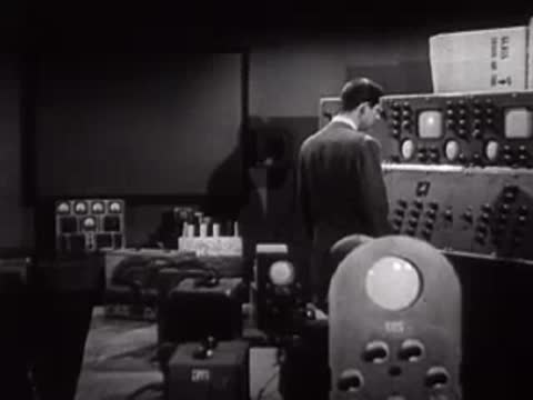 Wide view of a man operating electronic control equipment in a laboratory.