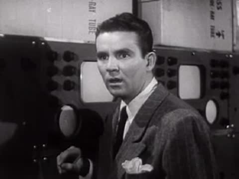 Man in suit looking sideways in a laboratory setting with equipment.