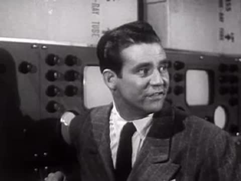 Man in suit speaking and turning in a laboratory setting.