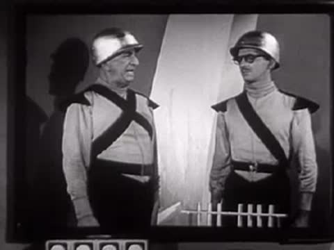 Two people in futuristic uniforms conversing in a studio set.