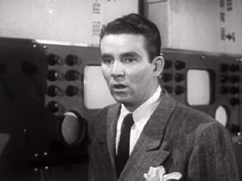 Man in suit speaking seriously in a laboratory setting.