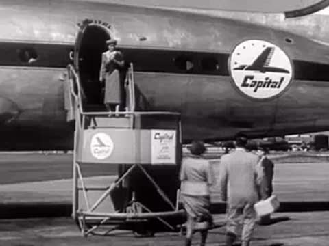 Passengers board a Capital Airlines propeller plane at an airport, mid-century.