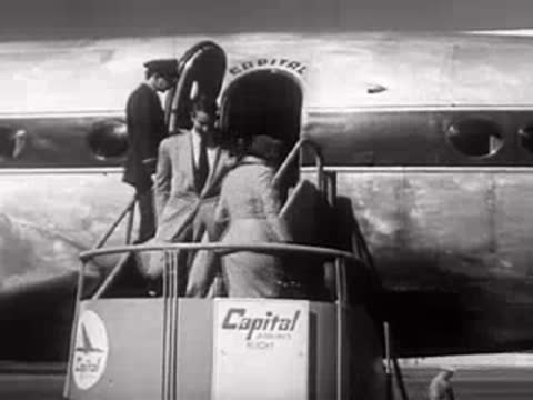 A propeller airplane on tarmac, boarding, and a car driving away, mid-century.