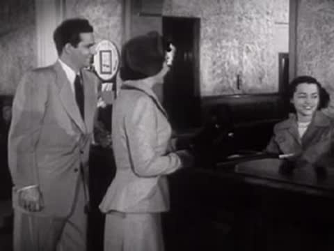 A man and woman approach a receptionist desk and talk, mid-century.