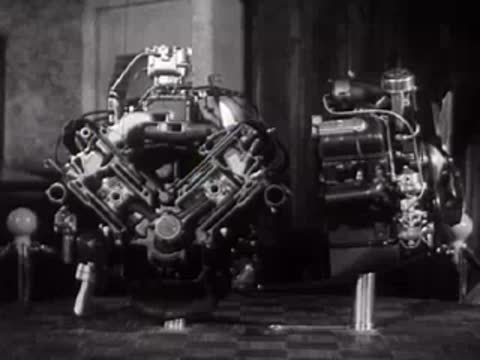 A large multi-cylinder engine mechanism on a rotating display stand.