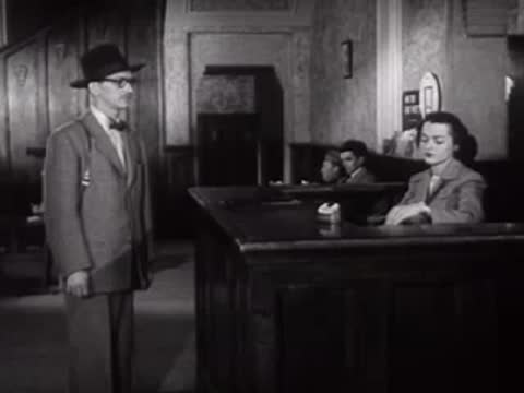 A man in a hat stands at a desk in a waiting room area.