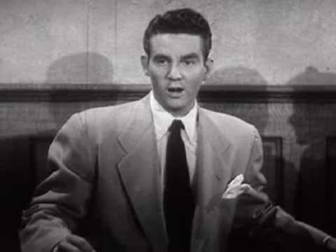 A man in a suit talking inside a building.