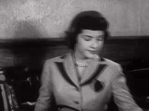 A woman sitting indoors and smiling.