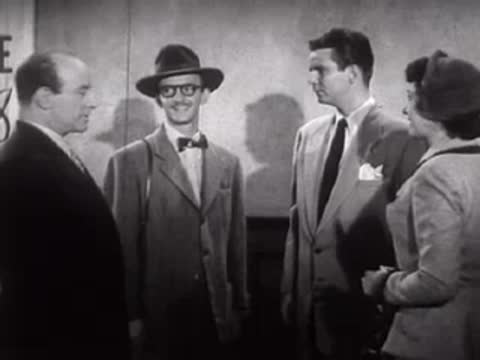 A group of people talking standing inside a room.