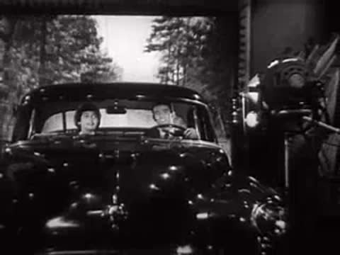 Car on a studio stage with a projection screen backdrop and crew.
