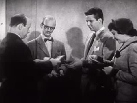 A group of people shaking hands and looking at a model.